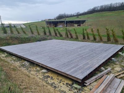 une grande terrasse en bois au milieu d'un champ