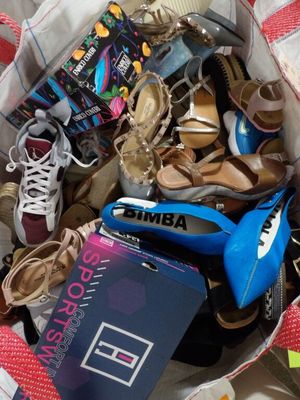 un sac rempli de chaussures et un livre par terre