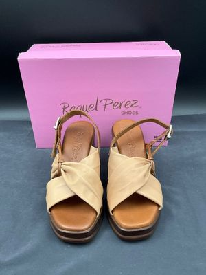 une paire de sandales beiges avec une boîte rose en arrière-plan