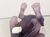 a glass figurine of a purple frog on a table