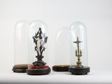 two glass cloches with statues inside of them