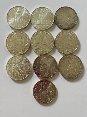 Plusieurs pièces de monnaie différentes sont disposées en triangle sur une surface blanche