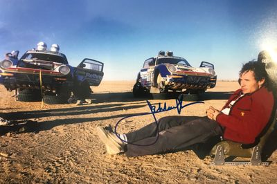une photo d'un homme assis par terre devant quatre voitures