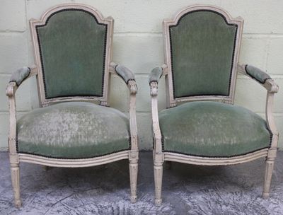 une paire de fauteuils rembourrés verts devant un mur de briques blanches