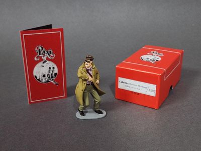 une figurine représentant un homme en imperméable, à côté d'une boîte rouge