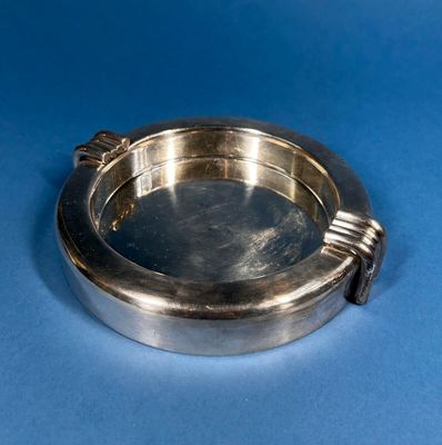 a silver plate with a handle on a blue surface