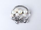 une broche composée de perles et de feuilles sur un fond blanc