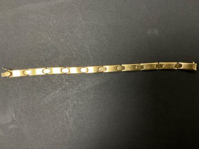 gros plan d'un bracelet en or sur une surface noire