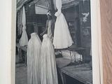 a black and white photo of a woman in a dress shop