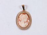 a close up of a gold pendant with a woman ' s profile