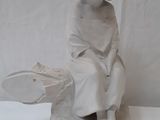 a statue of a boy sitting on a rock with a frisbee in his hand