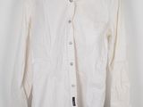 the white shirt is hanging on a hanger on the wall