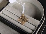 une croix en or montée sur une bague, dans un écrin