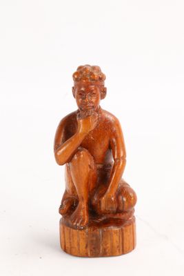 an old wooden statue of a man sitting on top of a wooden stump
