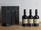 trois bouteilles de vin posées sur une table, à côté d'une boîte de livres