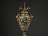 un grand vase en bronze orné de motifs en marbre vert, posé sur un socle