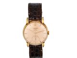 gros plan d'une montre sur une surface blanche avec un bracelet marron