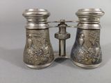 pair of antique silver plated binoculars on stand on grey background