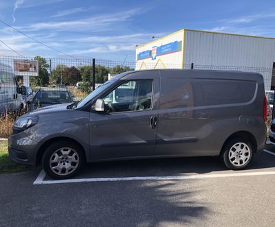 La camionnette grise est garée sur le parking à côté de l'immeuble.