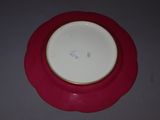 a red plate with a gold rim on a gray table