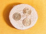 a small white plate with coins on it on a yellow surface