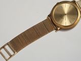 a close up of a gold watch on a white surface
