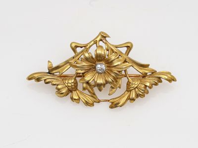 un gros plan d'une broche en or ornée d'un diamant au centre