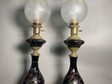 pair of black and gold vases with glass lamps on them