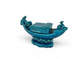 a small blue boat with people on it on a white surface