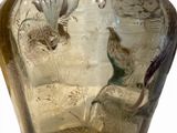 a glass vase with a bird on it sitting on a table