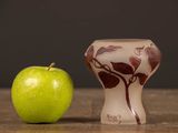 an apple next to a small vase on a table