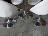 three white chairs and a table in a room with concrete flooring
