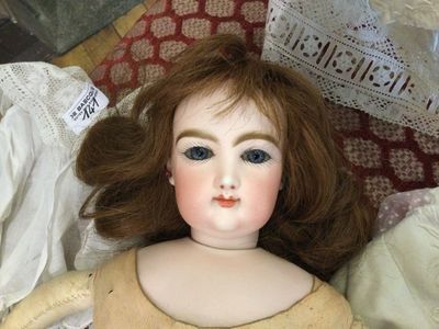a doll that is sitting on a bed with a pillow