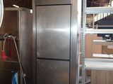 a silver refrigerator in the middle of a room with shelves