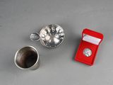 a small silver object and a red box on a table