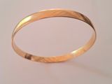 a close up of a gold bracelet on a white surface