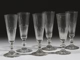 quatre verres à vin vides sont alignés sur une surface blanche