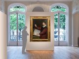a large painting of a man holding a book in a room