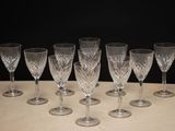 six wine glasses are lined up on a table with a black background