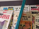a person holding a pair of chopsticks in front of a wall full of books