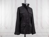 black jacket on a mannequin stand in front of a white wall