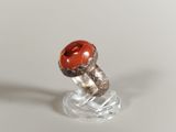 a ring with a red stone on it on a clear stand