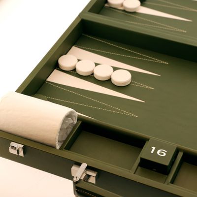 un plateau de backgammon vert avec des pions blancs et un rouleau de tissu