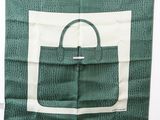 un sac à main vert et blanc posé sur un foulard vert et blanc