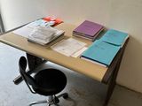un bureau avec des livres et une chaise devant une fenêtre