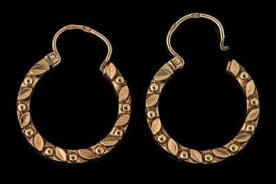 une paire de boucles d'oreilles en or sur fond noir