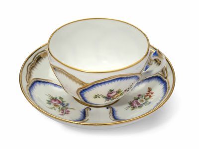 une tasse et une soucoupe sur une soucoupe sur une surface blanche