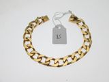 gros plan d'un bracelet en chaîne en or sur une surface blanche