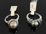 two rings with pearls and diamonds on a black surface