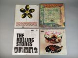 three rolling stones albums on a table with a flower in the middle